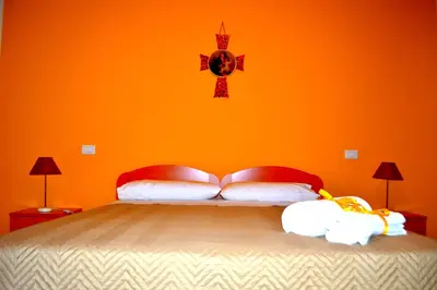 a bedroom with a bed with an orange wall at B&B Federico II in San Cipirello