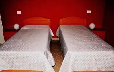 two beds in a room with red walls at B&B Federico II in San Cipirello