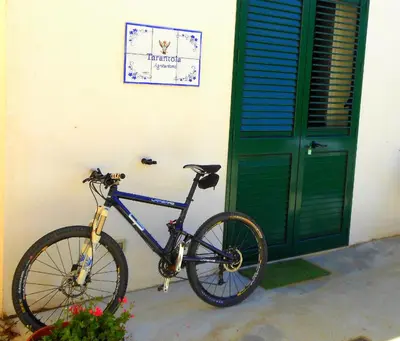 a bike parked next to a building with a green door at Agriturismo Tarantola in Alcamo
