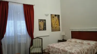 a bedroom with a bed and a chair next to a window at Demetra Rooms in Palermo