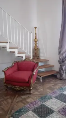 a living room with a red chair and stairs at Demetra Rooms in Palermo