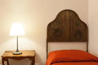 a bed with a headboard and a lamp on a table at Demetra Rooms in Palermo