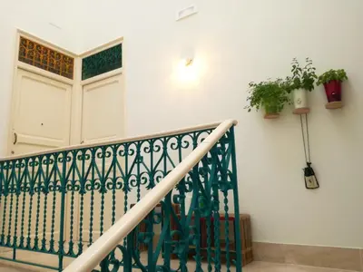 a staircase with a green railing and potted plants at Le Luminarie - Creative Residence in Balestrate