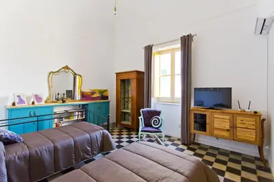 a bedroom with two beds and a tv and a mirror at Le Luminarie - Creative Residence in Balestrate