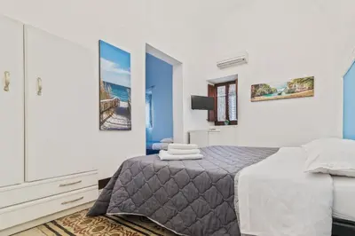 a bedroom with a bed with blue walls at Voilà Rooms Guest House in Terrasini