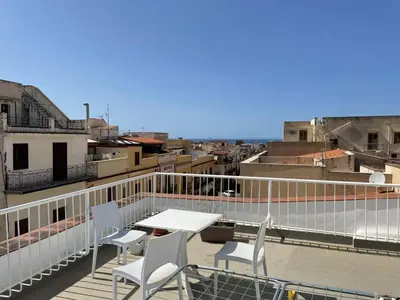a balcony with a table and chairs on a roof at Voilà Rooms Guest House in Terrasini