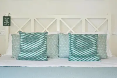 a bed with blue and white pillows on it at Villa Almyra in San Vito lo Capo