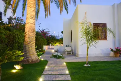 a garden with two palm trees and lights at Villa Almyra in San Vito lo Capo