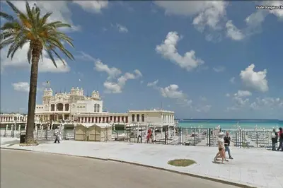 a large white building on the beach with a palm tree at BB45 in Palermo
