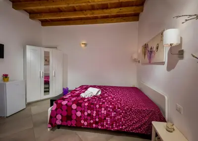 a bedroom with a red bed with pink sheets at Il Cortile in Castellammare del Golfo