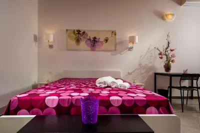 a room with a pink bed with a table at Il Cortile in Castellammare del Golfo