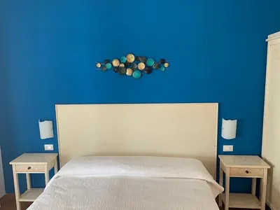 a bedroom with a blue wall with a bed and two tables at Villa Ancora Bed & Breakfast in San Vito lo Capo