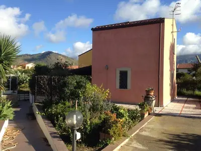 a building with a fence next to a garden at Le 3 tartarughe in Lascari
