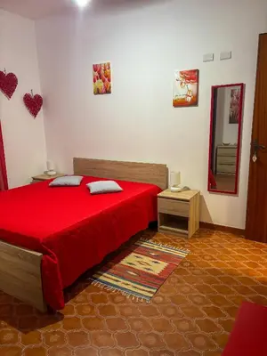 a bedroom with a red bed and a mirror at Alle Vigne Affittacamere in Alcamo