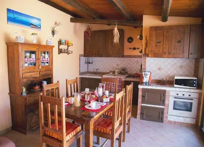 a kitchen with a wooden table and chairs and a kitchen with a stove at B&B Il Girasole in Balestrate