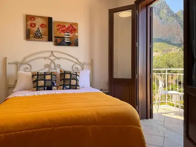 a bedroom with a bed with a yellow blanket and a balcony at Camere da Mariolina in Macari