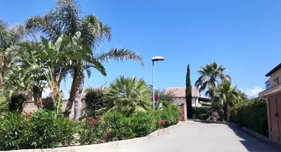 a street with palm trees and a building with a street light at Villa Camelie in Campofelice di Roccella