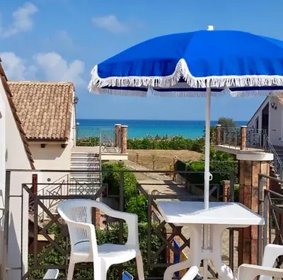 a table and chairs with a blue umbrella on a balcony at Villa Camelie in Campofelice di Roccella