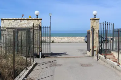 an open gate at the beach with the ocean behind it at Casa Vacanze Roccella Beach in Campofelice di Roccella
