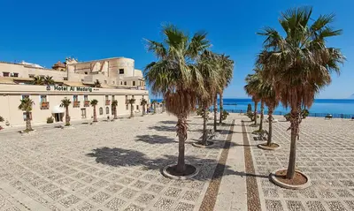 a row of palm trees in front of a building at Casa vacanza Nicuzza in Castellammare del Golfo