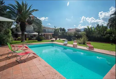 a swimming pool with two lawn chairs next to a house at Piccola Oasi in Mondello