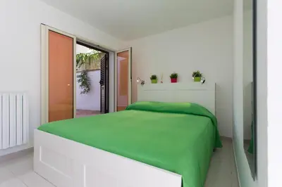 a white bedroom with a green bed and a window at Piccola Oasi in Mondello