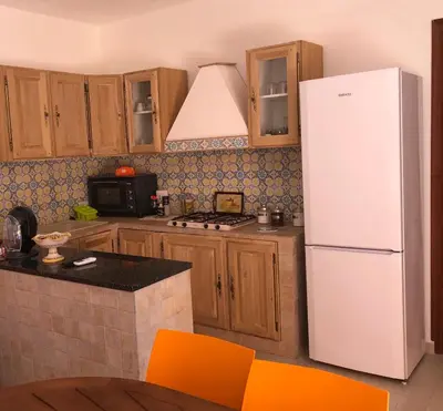 a kitchen with a white refrigerator and wooden cabinets at Appartamenti Cala Azzurra in Scopello