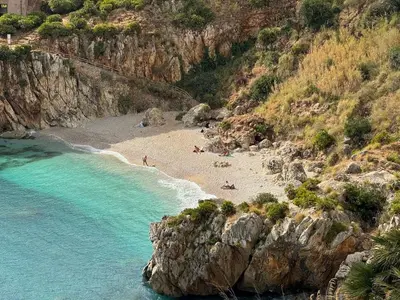 a beach with people laying on the sand and the water at holiday home LG in San Vito lo Capo