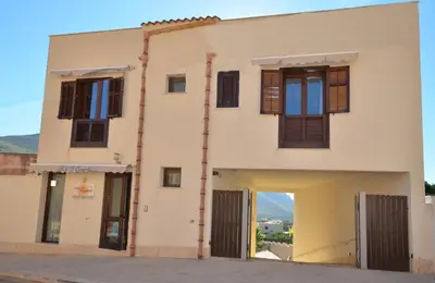a white building with brown shuttered windows at B&B Coppola in Castelluzzo