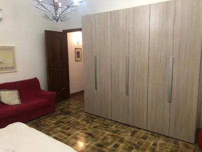 a bedroom with a large wooden cabinet and a red couch at Appartamento Vacanza Luna in Partinico