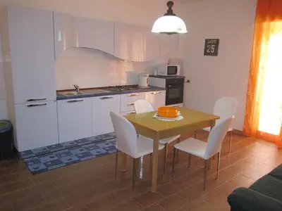a kitchen with a wooden table and white chairs at Appartamento Vacanza Luna in Partinico
