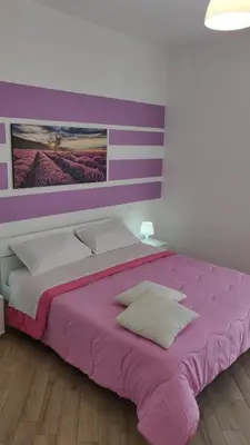 a bedroom with a large pink bed with pillows at White in Castellammare del Golfo