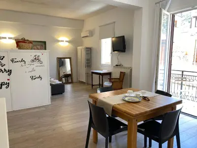 a living room with a dining room table and a kitchen at Residence Le Rose in Castellammare del Golfo