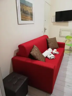 a red couch with pillows and a stool in a room at Appartamenti La Stella in Castellammare del Golfo
