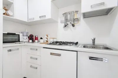 a white kitchen with white cabinets and a sink at Holiday & House - Imparato Vacanze Prestige Mondello in Mondello