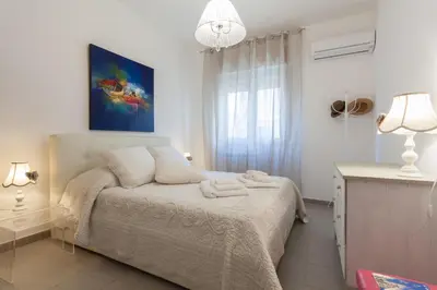 a white bedroom with a bed and a window at Holiday & House - Imparato Vacanze Prestige Mondello in Mondello