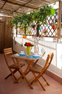 a wooden table with two chairs and flowers on a patio at Quattro Incanti in Palermo