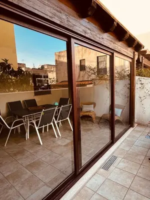 a patio with a table and chairs and windows at Sicilia Vacation in San Vito lo Capo