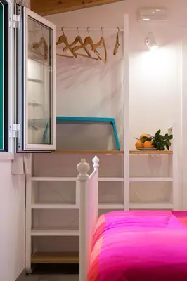 a bedroom with a pink bed and shelves at Nonna Anna Rooms in Palermo