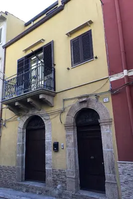 a yellow building with two doors and a balcony at Al Duomo in Partinico