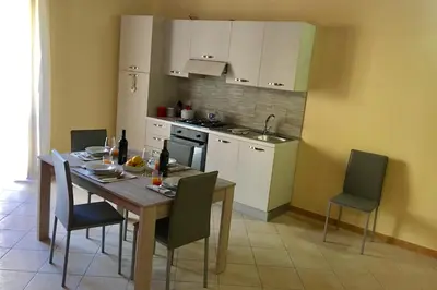 a kitchen with a wooden table and chairs and a kitchen with white cabinets at Al Duomo in Partinico