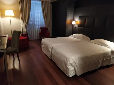 a bedroom with a large white bed and a red chair at Hotel Porta Felice & Spa in Palermo