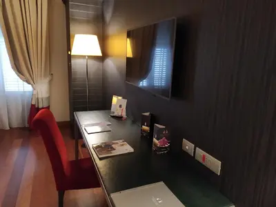 a room with a desk with a red chair and a lamp at Hotel Porta Felice & Spa in Palermo