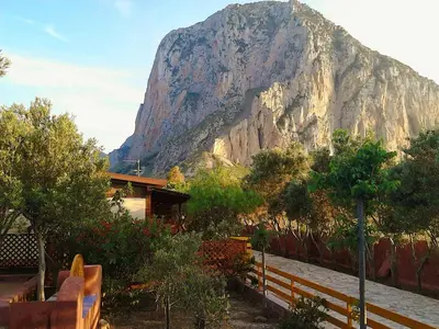 a mountain in front of a house with a fence at Baglio Del Sole in San Vito lo Capo