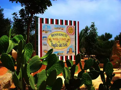 a large sign in a garden with a cactus at Baglio Del Sole in San Vito lo Capo