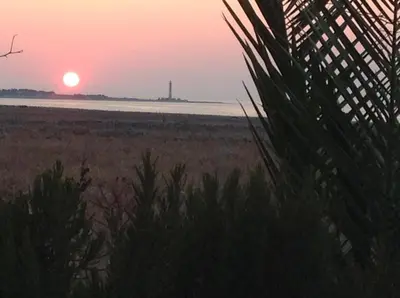 a sunset over a beach with a lighthouse in the distance at Baglio Del Sole in San Vito lo Capo