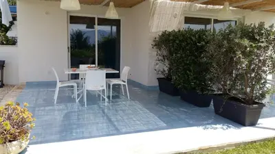 a table and chairs on a patio with plants at Isola del sole, Appartamenti con piscina in Balestrate
