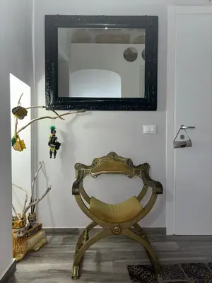 a chair in a room with a mirror on the wall at Le Alcove in Cinisi