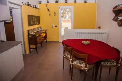 a kitchen and dining room with a red table and chairs at Tenuta Sperlinga - Il Campanile in Santa Flavia