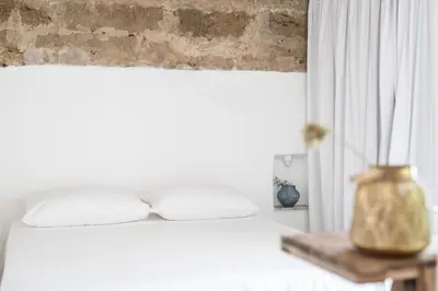 a bedroom with a white bed and a brick wall at Settegrana in Cinisi